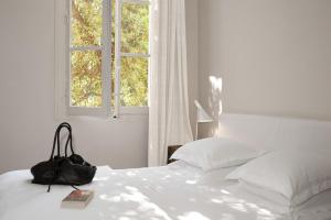 Una cama blanca con un bolso encima. en Maison Dauphine, en Aix-en-Provence