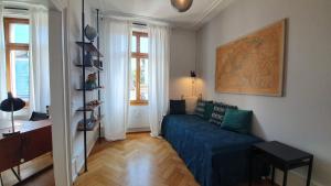 a living room with a blue couch and windows at Apartments by DASBREITEHOTEL in Basel