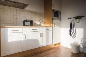 una cucina con mobili bianchi e un lavandino di T'hûs bed & breakfast a Katlijk Altre 36 foto