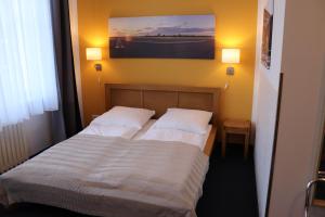a bedroom with two beds with white sheets and a painting at Hostel VITA Berlin in Berlin