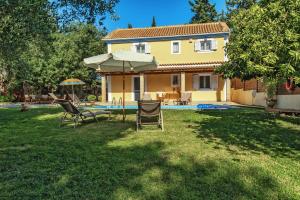 een tuin met stoelen en een parasol en een huis bij Villa Kardaris in Tragaki