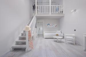 a white living room with a staircase and a couch at Adrina Beach Hotel in Panormos Skopelos