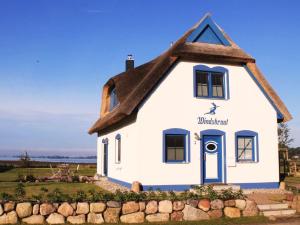 a small white house with a thatched roof at Reetdachhaus Windsbraut in Breege