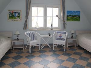 a bedroom with two beds and a desk and chairs at Reetdachhaus Windsbraut in Breege