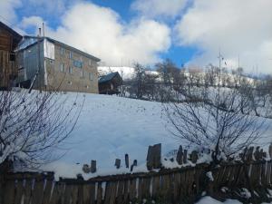 einen schneebedeckten Hof mit einem Zaun und einem Gebäude in der Unterkunft Guest House Luka in Danisparauli