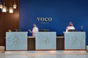 voco Al Khobar, an IHG Hotel في الخبر: رجل يقف على منصة التقديم أمام علامة voco