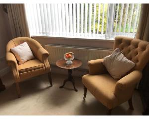 een woonkamer met 2 stoelen, een tafel en een raam bij Queens Road Rental - Winchester Accommodation in Winchester