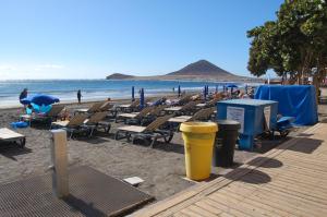 a beach with chaise lounges and chairs and the ocean at APARTAMENTOS LOS LAURELES in El Médano