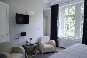 a bedroom with a bed and two chairs and a window at Domaine des Bruyères in Sains-en-Amiénois