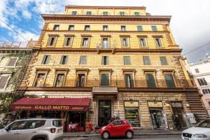 um edifício amarelo com um carro vermelho estacionado em frente dele em Cavour Attic with terrace em Roma