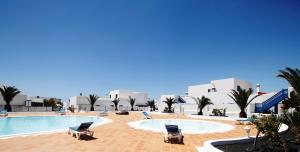 a large swimming pool with two chairs and buildings at Alojamiento Vacacional con balcón La Vela in Puerto Calero