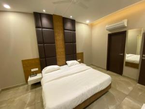 卢迪亚纳Hotel The Retro Regency的卧室里有一张白色的大床和一面镜子