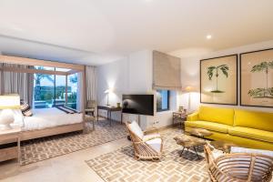 a hotel room with a king bed and a yellow couch at Finca Cortesin Hotel Golf & Spa in Casares
