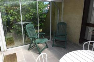 two green chairs sitting on a screened in porch at Réf 271, Seignosse Océan, Villa Patio au calme sous les pins, à quelques minutes de la plage et des commerces, 5 personnes in Seignosse