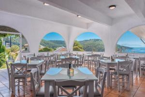 a restaurant with tables and chairs and windows at Adrina Beach Hotel in Panormos Skopelos