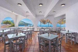 a restaurant with tables and chairs and a view of the ocean at Adrina Beach Hotel in Panormos Skopelos