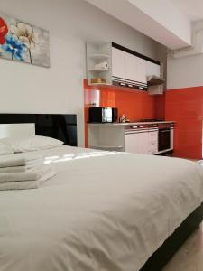 a bedroom with a large white bed and a kitchen at Center Apartments in Iaşi