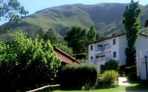 a white house with a mountain in the background at Las Ardillas Cabañas y Suites in La Falda