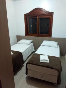 a bedroom with two beds and a window at Casa Das Fontes - Centro in Gramado