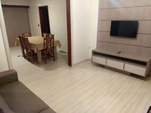 a dining room with a table and a flat screen tv at Casa Das Fontes - Centro in Gramado