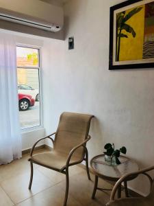 sala de estar con silla, mesa y ventana en Condo Mar Arena en Playa del Carmen