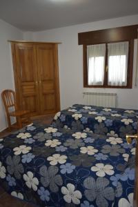 Un dormitorio con una cama con una manta azul con flores en Apartamentos Casa Esperanza - Ordesa, en Laspuña