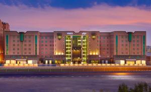 a large building with a lit up facade at night at voco Al Khobar, an IHG Hotel in Al Khobar