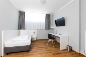 1 dormitorio con 1 cama, escritorio y TV en mk monteurzimmer eschborn, en Eschborn