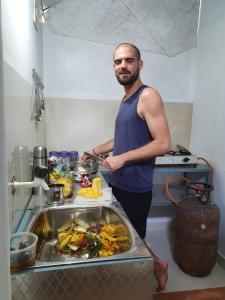 un hombre de pie en una cocina preparando comida en Cherai Ocean View Home en Cherai Beach