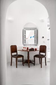 Oia Spirit Boutique Residences في أويا: طاولة غرفة طعام مع كرسيين ومرآة