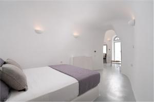 a bedroom with a white bed and white walls at Oia Spirit Boutique Residences in Oia