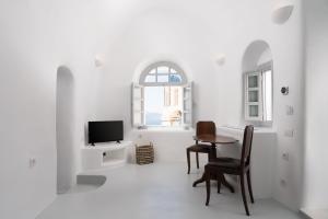 a white room with a table and chairs and a tv at Oia Spirit Boutique Residences in Oia