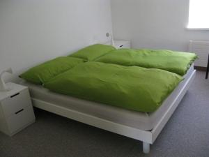 a bed with green sheets and pillows on it at Tgesa La Niva 1 in Savognin
