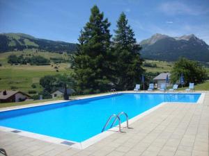 a large blue swimming pool with mountains in the background at Tgesa Sunnmatt Nr. 13 in Savognin