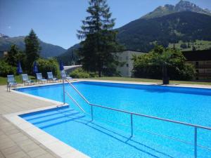 a large blue swimming pool with chairs and a mountain at Tgesa Sunnmatt Nr. 13 in Savognin