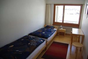1 dormitorio con 2 camas, mesa y ventana en Tgesa Marlotscha en Savognin