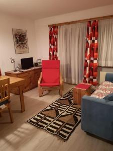 a living room with a red chair and a desk at Curtinfess Rezzonico in Bivio