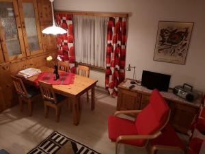 a living room with a table and a red chair at Curtinfess Rezzonico in Bivio