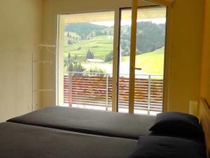 a bed in a room with a large window at Sandeilas 10 in Savognin