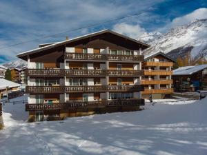 a building in the snow in front of a mountain at Haus Alfa in Saas-Fee