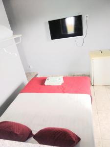 1 cama blanca con almohadas rojas en una habitación en Pousada Balbino, en Cabo Frío