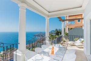 a balcony with white chairs and a view of the ocean at Villa La Terrasse Palheiro Village with private pool by HR Madeira in São Gonçalo