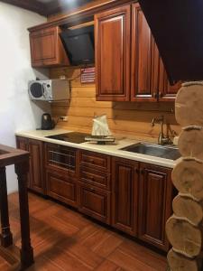 una cocina con armarios de madera y fregadero en Holiday House Karavella en Abzakovo