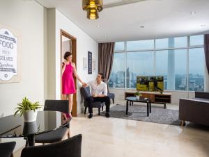 a woman standing next to a man in a living room at The Penthouse KLCC - Suite & Duplex 57F Sky Residence in Kuala Lumpur