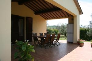 un patio con tavolo e sedie in una casa di Graziosa casetta con Piscina a Castagneto Carducci
