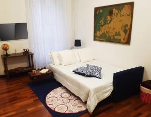 a bedroom with a white bed with a rug at Ricordi di Viaggio, maison retrò in Trieste