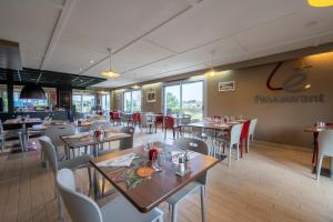 uma sala de jantar com mesas e cadeiras e um restaurante em Campanile Lorient - Lanester em Lanester