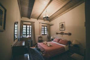 a bedroom with a bed and a desk and windows at Bourazani Wild Life Resort in Konitsa