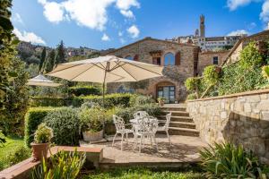 une terrasse avec une table, des chaises et un parasol dans l'établissement Porta Castellana B&B - Apartment, à Montalcino