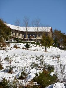 ein Haus auf einem verschneiten Hügel mit einem Gebäude in der Unterkunft Oficina Do Joe Guesthouse in Outeiro